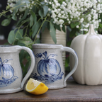 Rowe Pottery Hand thrown stoneware mug In a hand decorated pumpkin pattern with decorative background