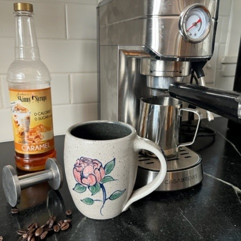 Rowe Pottery Hand thrown stoneware mug In a hand decorated Peony pattern with coffee maker and grounds in the background